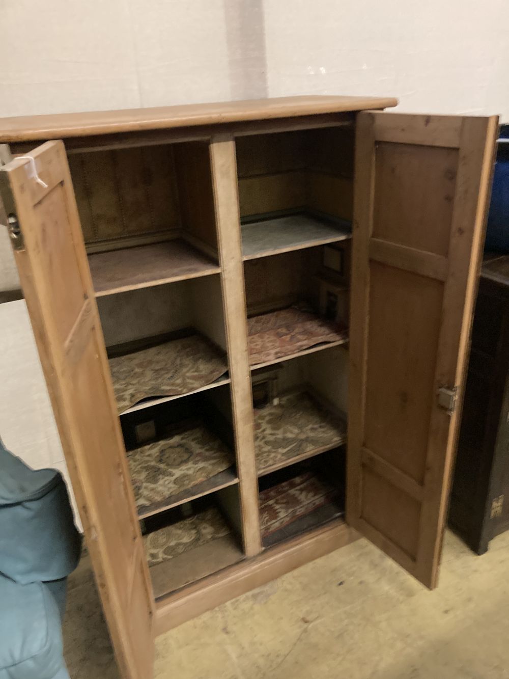 A collection of dolls and dolls house furniture displayed in room settings in a pine cupboard, width 84cm, depth 36cm, height 132cm